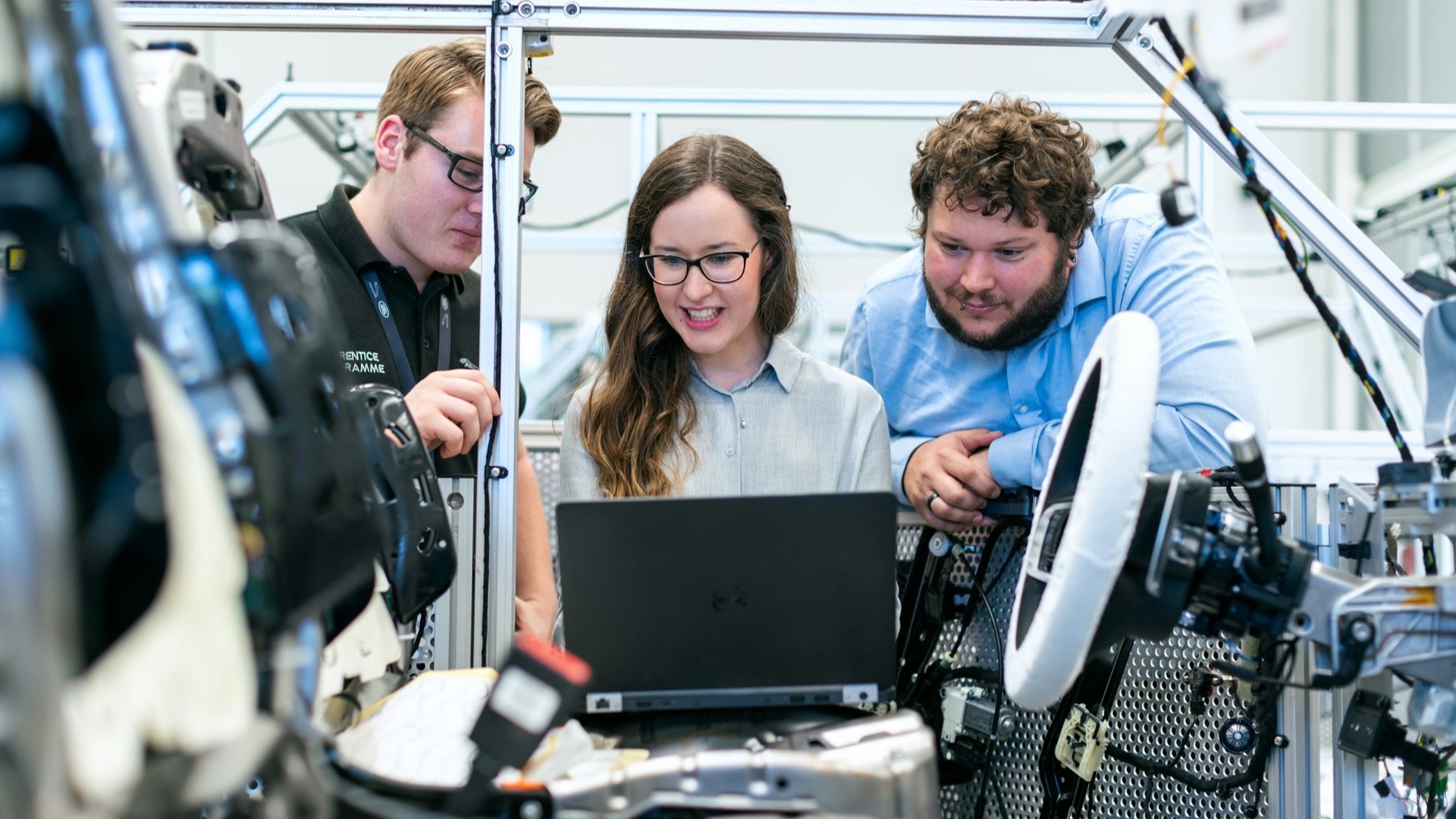 Engineering team reviewing work on a laptop in a bright workshop